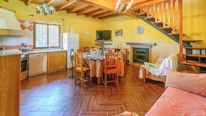 A kitchen with wooden cabinets, a dining table with chairs, a fireplace, and a staircase. - Las Lomas de San Rafael Periana by Ruralidays (Málaga)