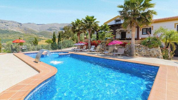 A swimming pool with lounge chairs and umbrellas, surrounded by palm trees and a mountain view. - Las Lomas de San Rafael Periana by Ruralidays (Málaga)