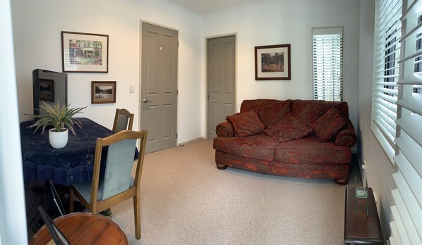 A living room with a dark blue table, a red patterned sofa, and a potted plant.