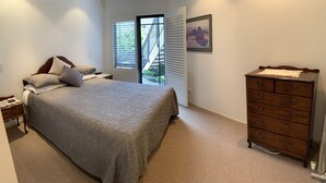 A bedroom with a bed, a dresser, a nightstand, a window with blinds, and a framed picture on the wall. - Apartment Ahuriri short stroll to beach.<br> (Ahuriri)