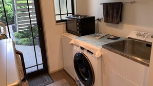 A compact kitchen with a washing machine, microwave, and a sink. - Apartment Ahuriri short stroll to beach.<br> (Ahuriri)