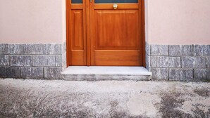 Eine Holztür mit Glasfenster, eine kleine Veranda und ein Schild mit der Nummer 9 an der Wand.