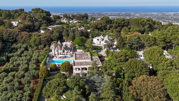 Luchtbeeld van een resort met een zwembad, omgeven door weelderige begroeiing en traditionele architectuur.