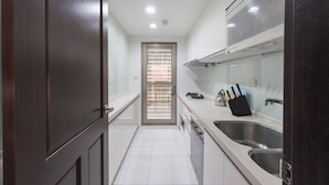 Una cocina moderna con armarios blancos, electrodomésticos de acero inoxidable y un ventanal con persianas.