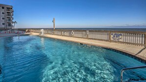 A swimming pool with a wooden deck and a lifeguard stand, surrounded by a high fence with warning signs. - Oceanfront Oasis w/ Deck and Resort Beach Access! (Garden City)