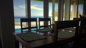 Un espace repas avec vue sur la plage et l’océan.