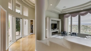 A spacious living area with a large window, a flat-screen TV, and a fireplace. - Golfers Paradise in Fountain Hills (Fountain Hills)