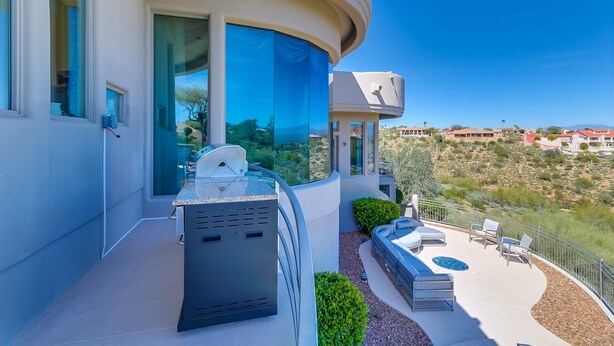 A modern building with large windows, a curved balcony, and a pool area with lounge chairs. - Golfers Paradise in Fountain Hills (Fountain Hills)