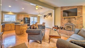 Amplia sala de estar con chimenea, cocina con alacenas de madera y comedor con un gran ventanal.