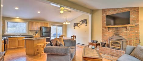A spacious living area with a fireplace, a kitchen with wooden cabinets, and a dining area with a large window.