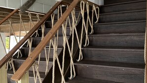 Un escalier en bois avec des rampes en corde et une main courante en bois.