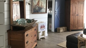 Une pièce avec une commode en bois, un grand miroir, un tableau et une porte bleue.
