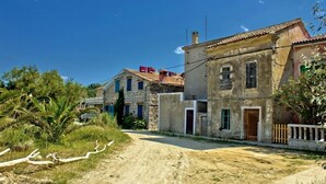 A rural road leading to a stone building with a tiled roof, surrounded by greenery and palm trees. - Room in Susak with Air condition, WIFI (3865-3) (Susak)