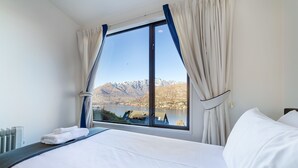 Habitación de hotel con un ventanal que ofrece vistas a montañas y un lago.