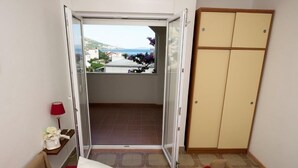 A room with a bed, a wardrobe, a small table with a lamp, and a view of the outside balcony. - Apartment in Duće with Seaview, Terrace, Air condition, WIFI (132-9) (Duce)