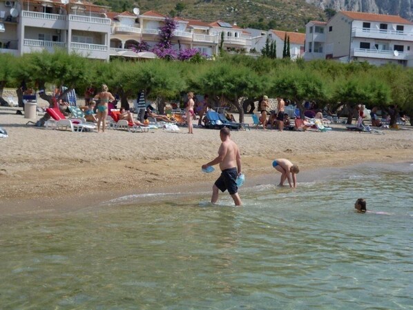 A beach with people sunbathing and swimming.
