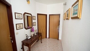 Un pasillo con una consola de madera, un espejo y cuadros en las paredes.