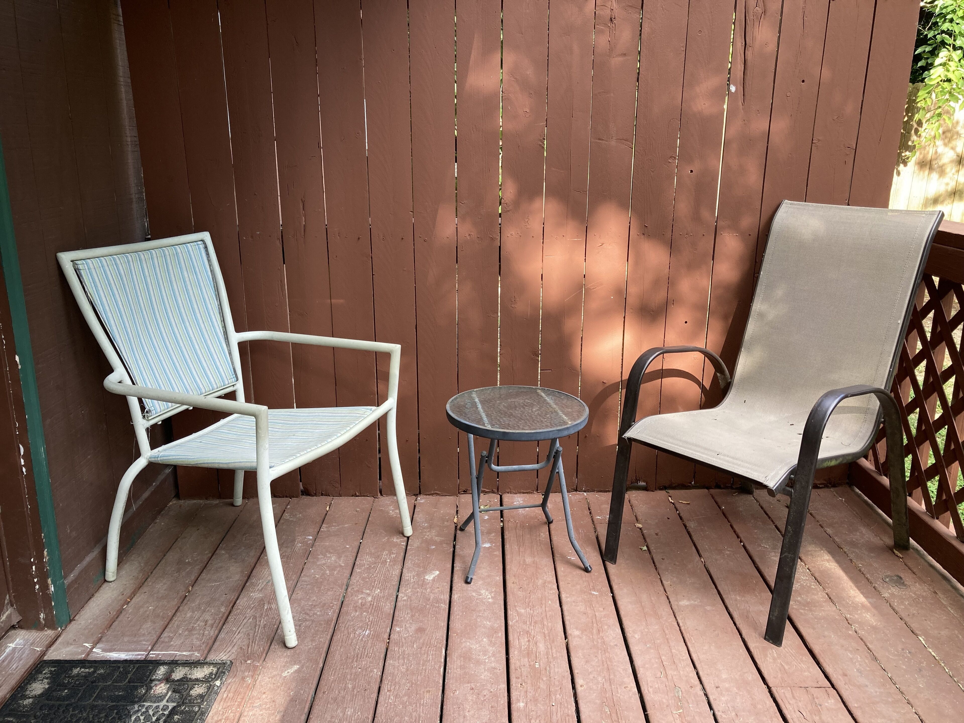 Eine Holzterrasse mit zwei Stühlen und einem kleinen runden Tisch.