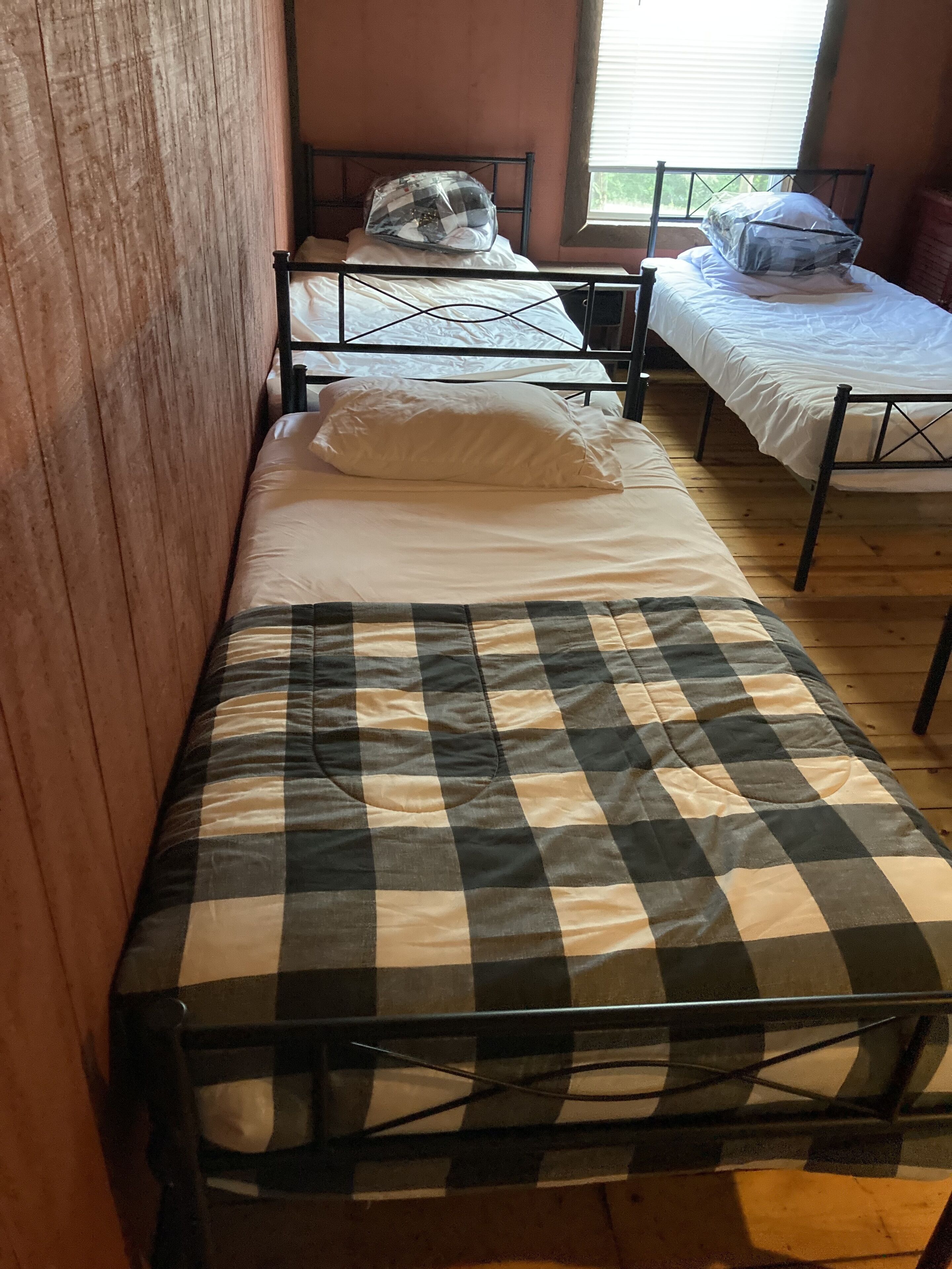 A dormitory room with two single beds, each with a mattress and pillow.