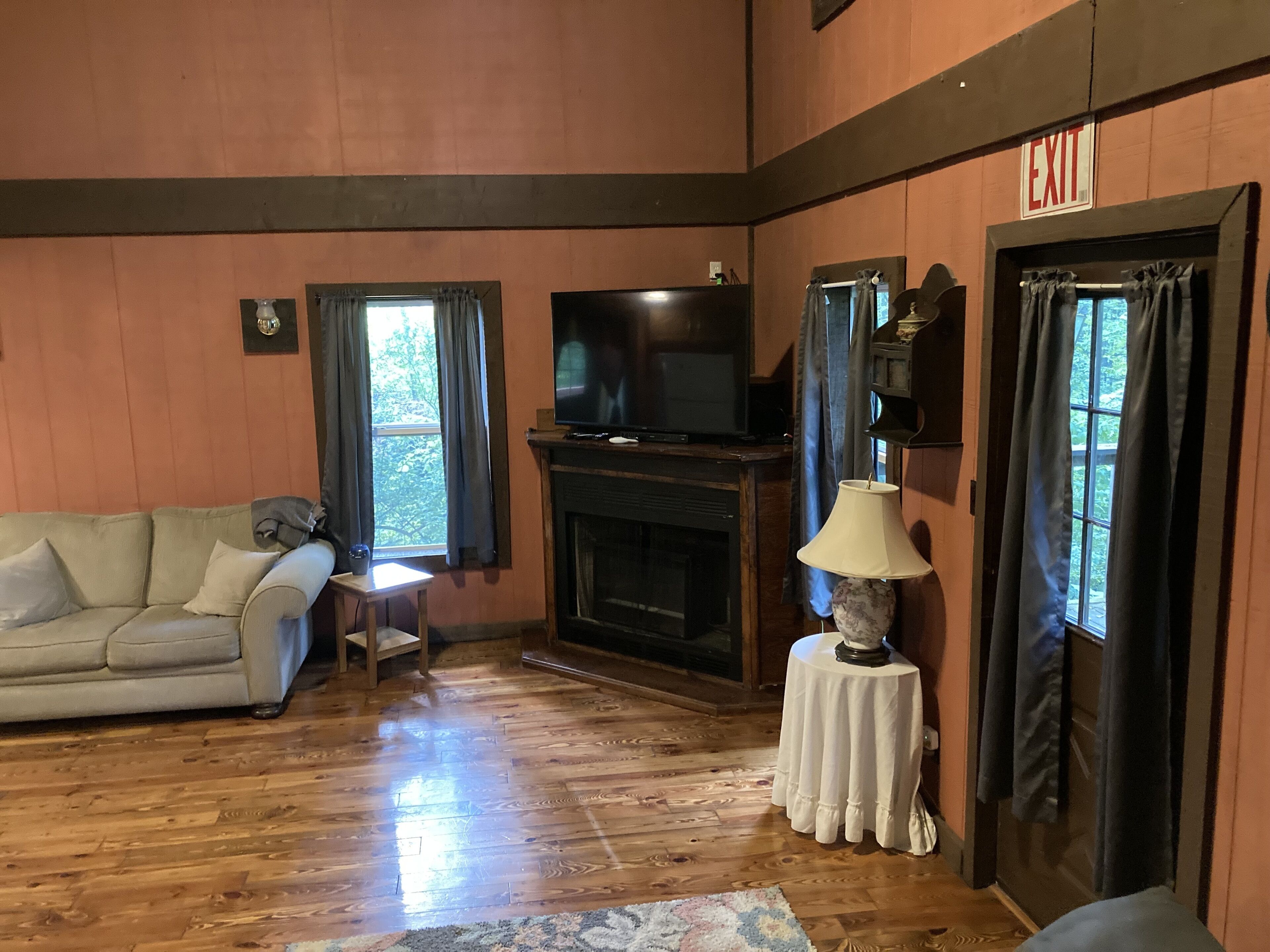 Una sala de estar acogedora con un sofá, un televisor, una chimenea y una pequeña mesa con una lámpara.