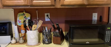 A kitchen with wooden cabinets, a microwave, a toaster, and various kitchen utensils.