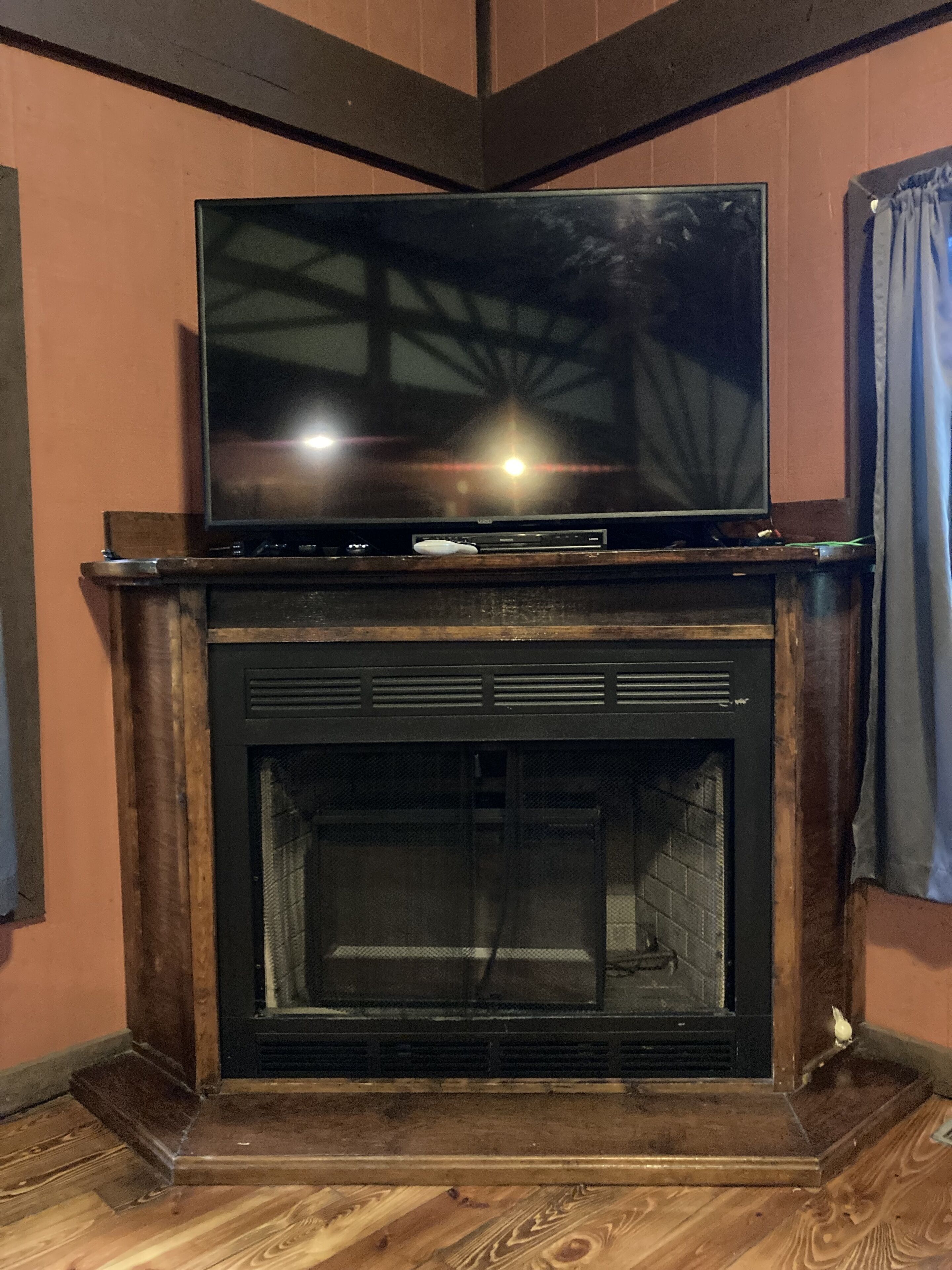 Un téléviseur à écran plat est posé sur une cheminée en bois, au-dessus du foyer.