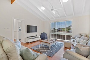A modern living room with a flat-screen TV, a coffee table, and a sofa set.
