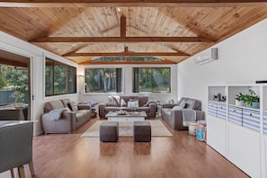 A spacious living room with a high ceiling, large windows, and a modern interior design.