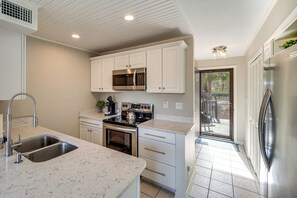 A kitchen with white cabinets, stainless steel appliances, a double sink, and a view to the outside.