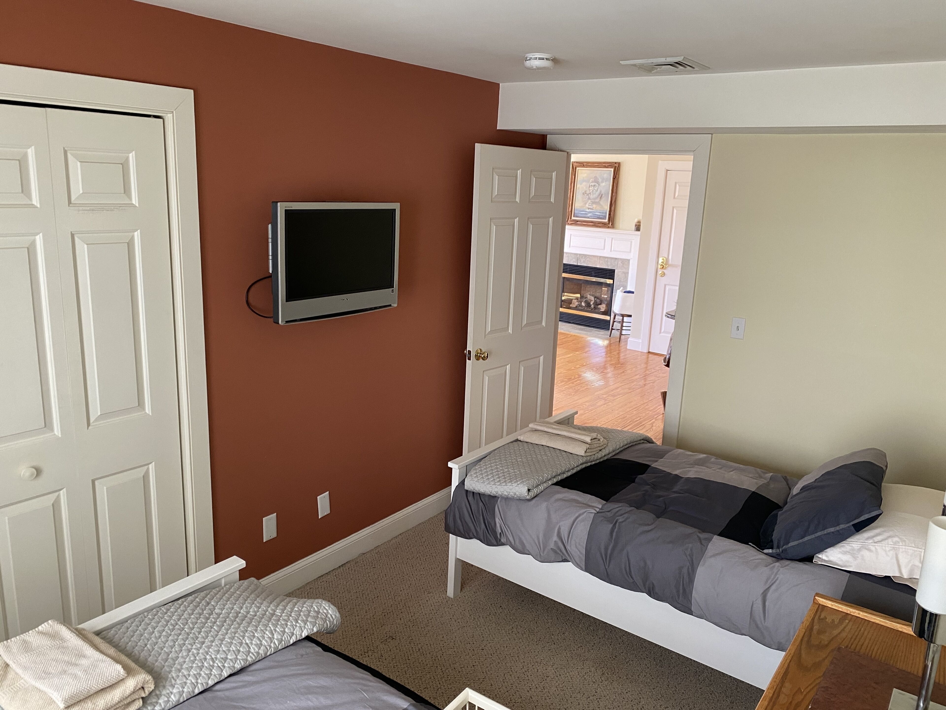 A bedroom with a bed, a TV, and a door leading to another room.
