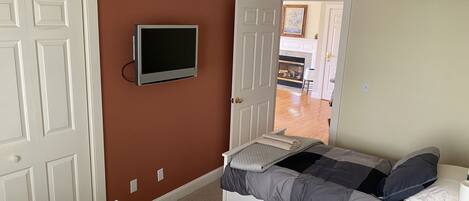 A bedroom with a bed, a TV, and a door leading to another room.