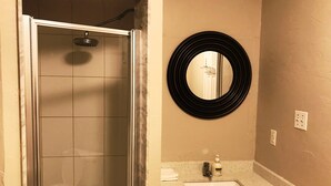 A bathroom with a shower, a sink, and a mirror. - Guardian Cottage (Mississauga)