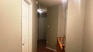 A hallway with wooden flooring, white doors, and a wooden staircase with a handrail. - Guardian Cottage (Mississauga)