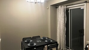 A dining area with a table set for four, black chairs, and a chandelier. - Guardian Cottage (Mississauga)