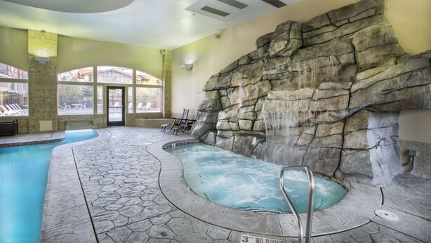 An indoor pool with a rocky wall and a 3 ft no diving sign.