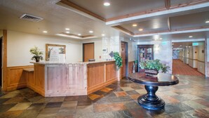 A reception area with a wooden counter, a round table with a black base, and a tiled floor.
