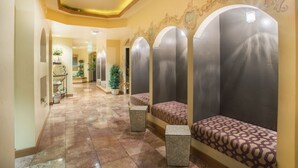 A hallway with a tiled floor, benches, and a plant.