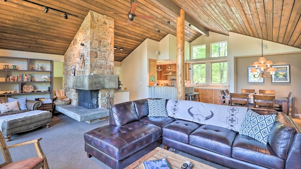 Ein gemütliches Wohnzimmer mit Kamin aus Stein, Ledersofas und einer Essecke mit Holztischen und -stühlen.