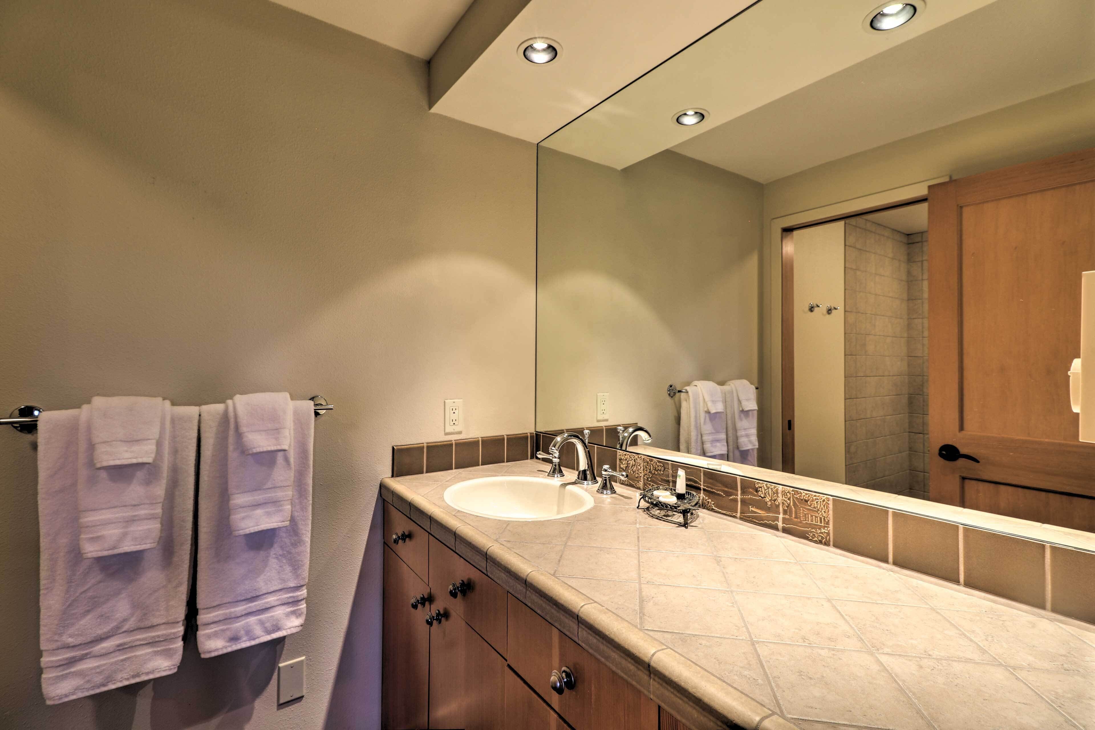 A modern bathroom with a large mirror, a sink, and two towels hanging on a rack.