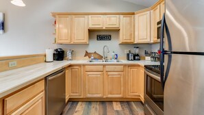 A modern kitchen with wooden cabinets, stainless steel appliances, and a 'KITCHEN' sign. - Accommodating Anchorage Abode < 1 Mi to Jewel Lake (Anchorage)