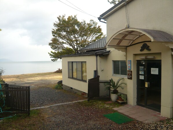 A building with a beach view, a small porch, and a sign indicating it is a coffee shop.