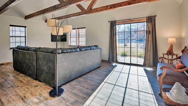 A spacious living area with a large sectional sofa, a floor lamp, and a view through a large window.