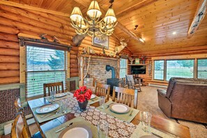 A log cabin interior with a dining area, fireplace, and a cozy living room. - Secluded Retreat w/ Wood Stove, 11 Mi to Bozeman! (Gallatin Gateway)