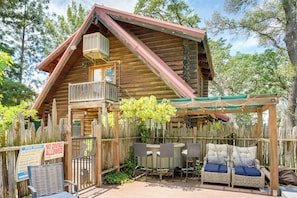 En træhytte med balkon, udendørs møbler og et skilt, hvor der står 'Dykning forbudt'.