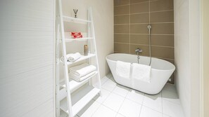 A modern bathroom with a freestanding bathtub, white shelves with towels, and a shower with a handheld showerhead. - Flat 6 pers - modern, central, ski in ski out (Châtel)