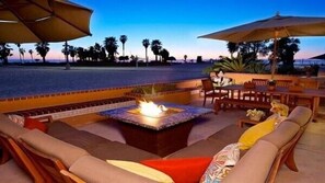 Un espace extérieur aménagé avec un foyer, des sièges confortables et une vue sur la plage.