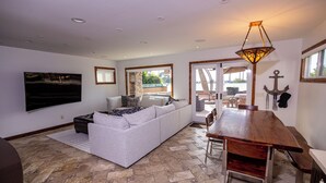 A living room with a sofa, a wooden dining table, and a view of the outdoors.