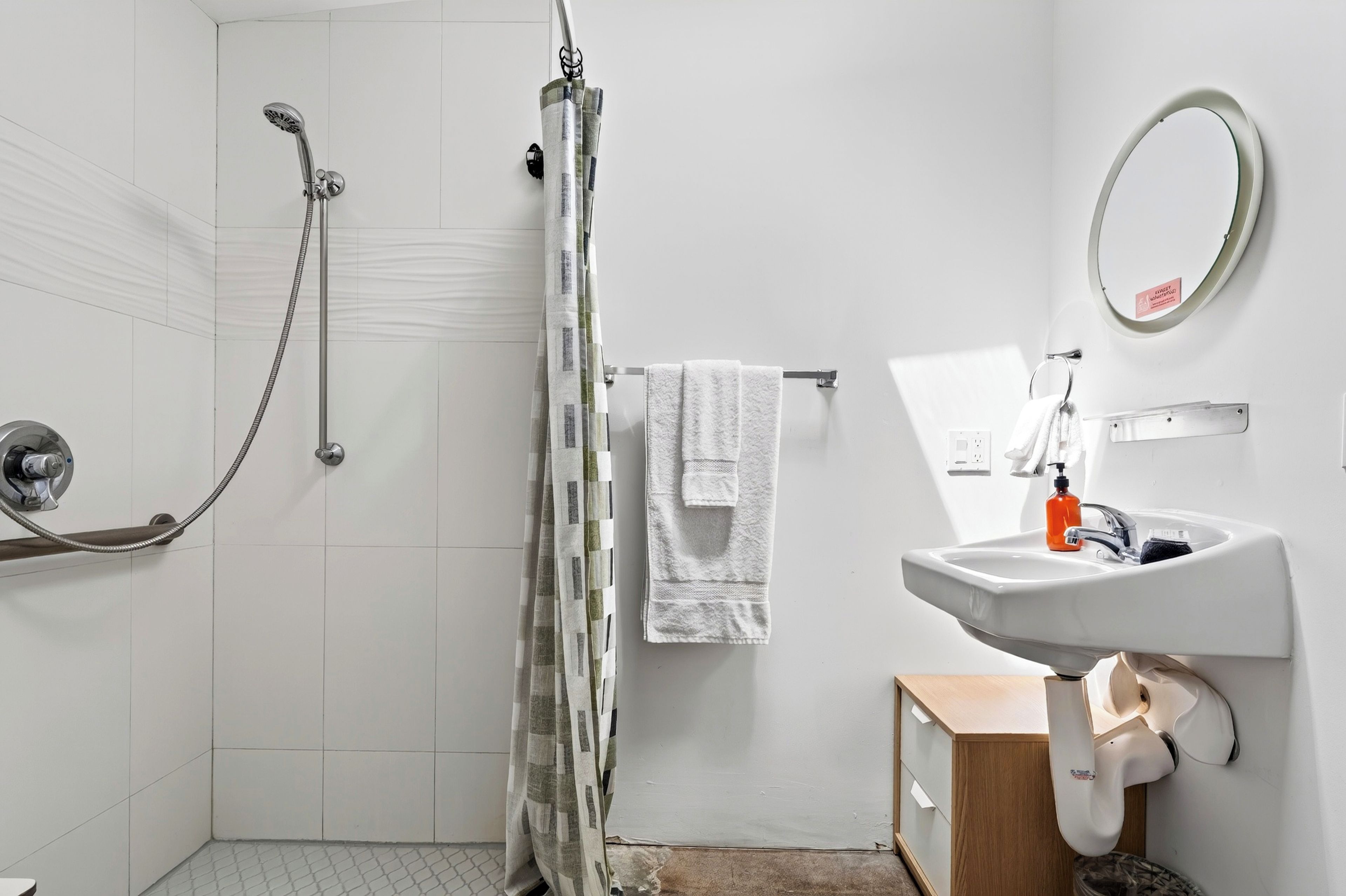 Un baño con ducha, lavamanos y espejo.
