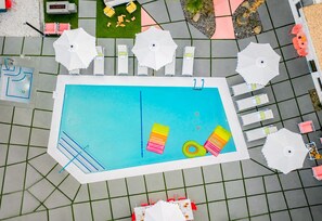 Une piscine entourée d’une terrasse carrelée, agrémentée de chaises longues et de parasols.