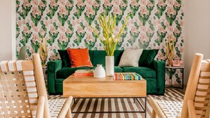 A living room with a green sofa, a wooden coffee table, and a patterned wallpaper. - The Wesley by AvantStay (Palm Springs)